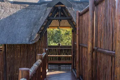 an entrance to a thatched building with a wooden fence at Kruger Park Lodge Unit No. 209 in Hazyview