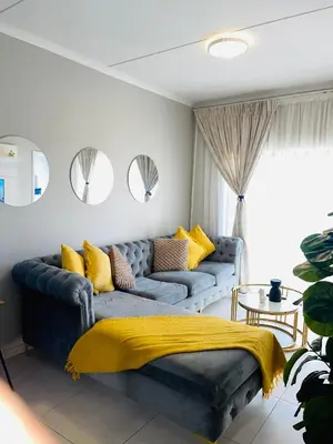 a living room with a blue couch with yellow pillows at Dubai 2 in Midrand