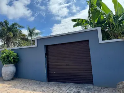a blue garage door with a plant next to it at Spacious stay-in bachelor apartment in Kempton Park