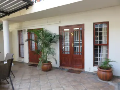 a house with wooden doors and potted plants on a patio at Harties Lodge - Bay View 5 in Hartbeespoort