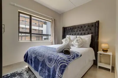 a bedroom with a large bed and a window at GroundEazy beside Mall of Africa in Midrand