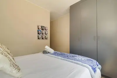 a bedroom with a white bed and a cabinet at GroundEazy beside Mall of Africa in Midrand