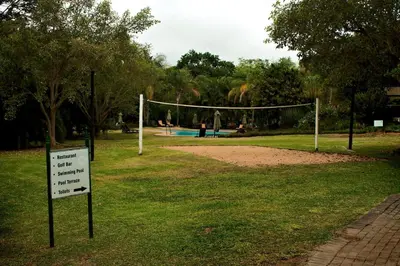 a volleyball net in a park with a sign in the grass at Kruger Park Lodge - Private Villa 514 in Hazyview