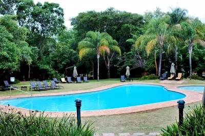 a swimming pool in a park with palm trees at Kruger Park Lodge - Private Villa 514 in Hazyview