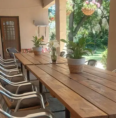 a long wooden table with chairs and plants on it at Ilnika Farm Stay in Naboomspruit