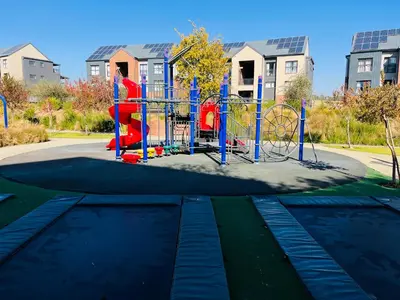 a playground in a park in front of some buildings at Secure 1 Bedroom Apartment in Midrand, Waterfall City - Lock Up and Go - Free WIFI and Parking - 5 Elizabeth Place in Midrand