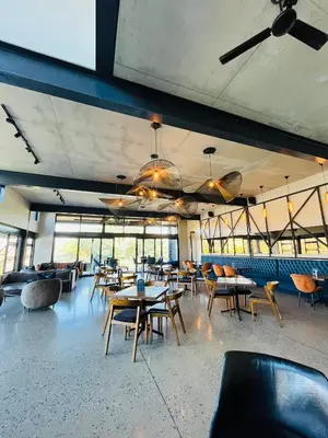 a dining room with tables and chairs and windows at Spacious 2 Bedroom Apartment in Midrand, Waterfall City - Business and Family friendly - 10 Elizabeth Place in Midrand