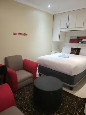 a room with a bed and a couch and a chair at The wood Guest house in Pretoria
