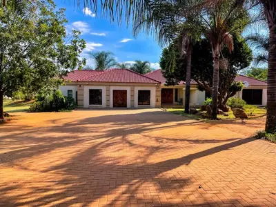 a house with palm trees and a brick driveway at Bobisemo Luxury Pretoria East Apartment in Tierpoort