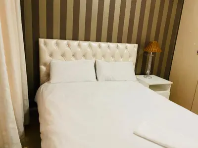 a bedroom with a large white bed and a lamp at Siena Sun Apartment 10 in Midrand