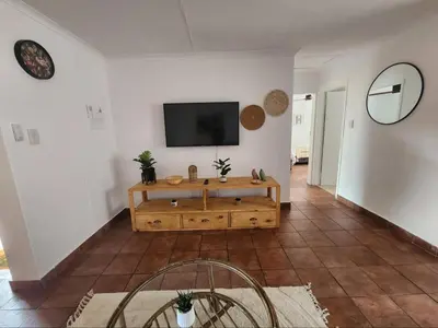 a living room with a television on a white wall at Baruch in Pretoria