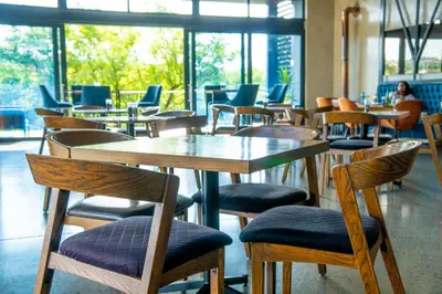 a restaurant with wooden tables and chairs and windows at Secure 1 Bedroom Apartment in Midrand, Waterfall City - Lock Up and Go - Free WIFI and Parking - 9 Elizabeth Place in Midrand