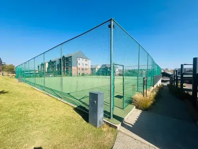 a tennis court with a net on a field at 4 Elizabeth Place - Beautiful 1 bedroom unit next to Kyalami Racetrack with free WiFi swimming pool gym and restaurant - Perfect for a Couple in Midrand Waterfall in Midrand