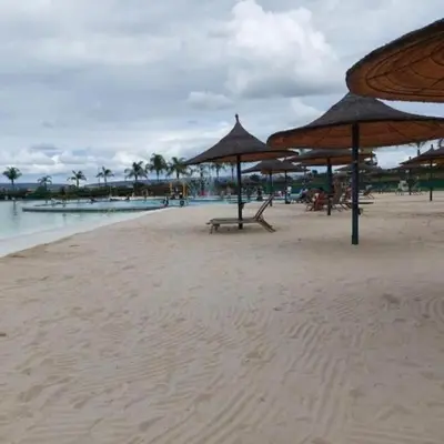 a beach with tables and umbrellas on the sand at Kayalako at The Blyde - Blue Crystal Lagoon in Pretoria