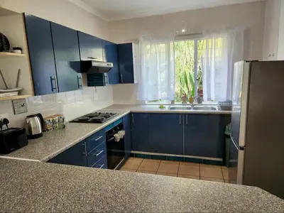 a kitchen with blue cabinets and a sink and a window at Selah, self-catering in Pretoria
