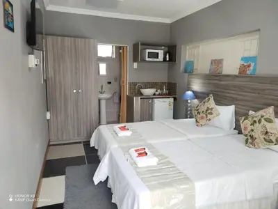 a bedroom with a large white bed and a bathroom at FUMODS guest house in Pretoria