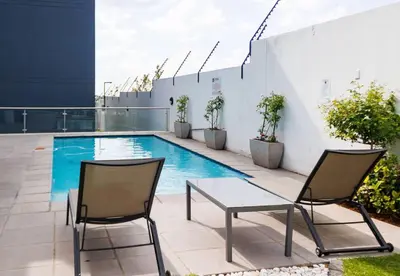 two chairs and a table next to a swimming pool at Luminant Escapes - with power backup in Midrand