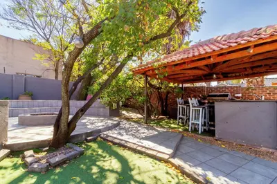 a backyard with a tree and a wooden pergola at Cheerful Cottage in Johannesburg