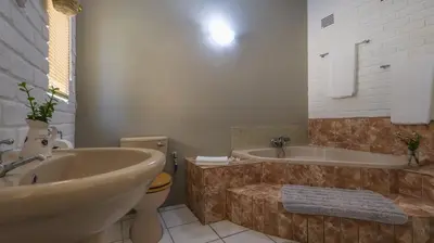 a bathroom with a tub and a toilet and a sink at Stay at Percy Self Catering House in Nelspruit