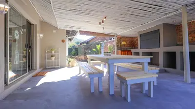 a patio with a table and benches on a house at Stay at Percy Self Catering House in Nelspruit