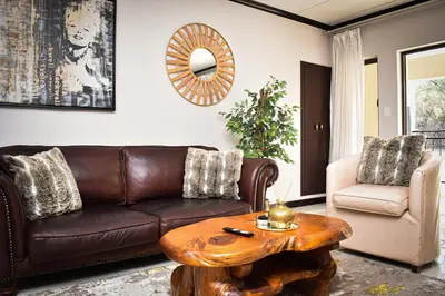 a living room with a brown couch and a table at Walford Estate, Spacious Private, Modern luxury living in Midrand