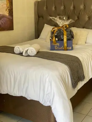 a bed with a gift box on top of it at Whizzy Lifestyle Lodge in Witbank