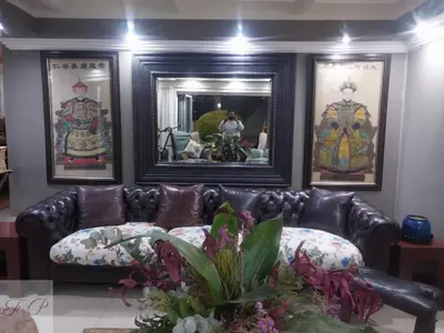 a leather couch in a living room with pictures on the wall at The Flamingo Suite at Frederick's Place in Pretoria