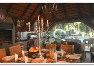 a dining room with a table with a chandelier at The Flamingo Suite at Frederick's Place in Pretoria