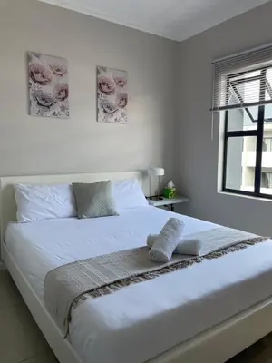 a white bed with two pillows on it in a bedroom at 1 Bedroom Sleek, Spotless, Work-from-home Sanctuary in Midrand
