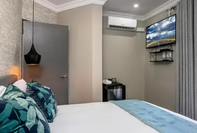 a bedroom with a bed and a tv on the wall at Woman Era Guesthouse in Midrand