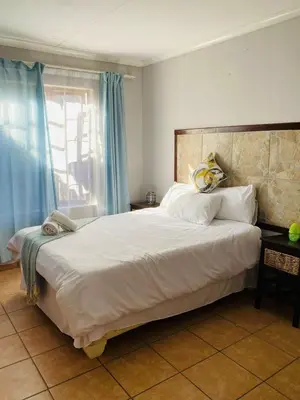 a bedroom with a large white bed with blue curtains at Nteto guesthouse in Dwarsloop