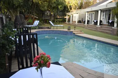 a swimming pool with a vase of flowers on a table at The Elephant Room at Frederick's Place in Pretoria