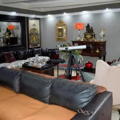 a living room with a black leather couch at The Elephant Room at Frederick's Place in Pretoria