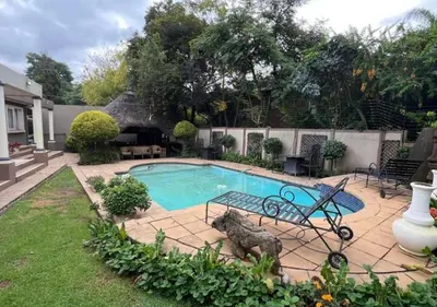 a swimming pool with a statue of a dog in a yard at The Elephant Room at Frederick's Place in Pretoria