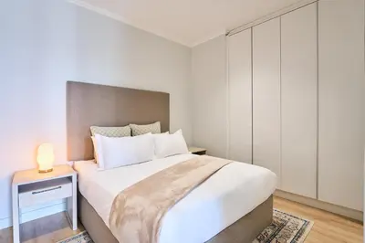 a bedroom with a large bed and a night stand at 8's at Ellipse Waterfall in Midrand
