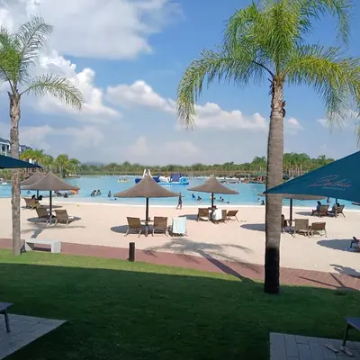 a beach with chairs and umbrellas and a body of water at The Blyde 2-Bed Luxe Apartment in Pretoria