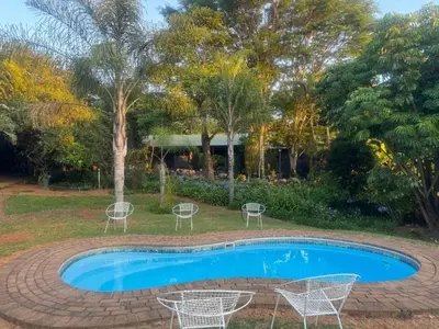 a swimming pool with chairs and a table at Busa House Self-Catering Unit in White River