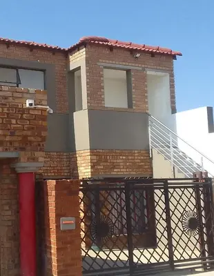 a brick house with a metal gate and stairs at Thiwani Guest House in Kempton Park