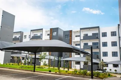 an umbrella in a parking lot in front of a building at Eirini Elegant - Hermes Apartment in Midrand