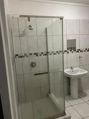 a shower with a glass door next to a sink at Travelers Standard in Kempton Park