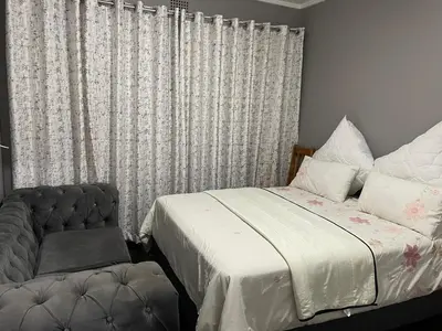 a bedroom with a bed and a chair and a window at Torremolinos City in Kempton Park