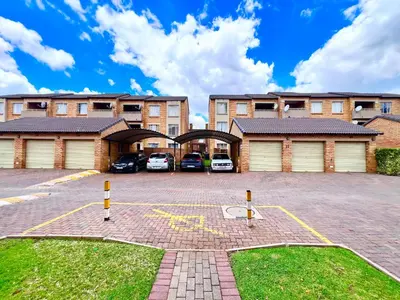 a parking lot in front of a building with cars at Centurion La Creme Apartments in Centurion