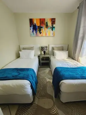 a room with two beds and a painting on the wall at 2d - 50 No load shedding - 2 bedroom in Centurion