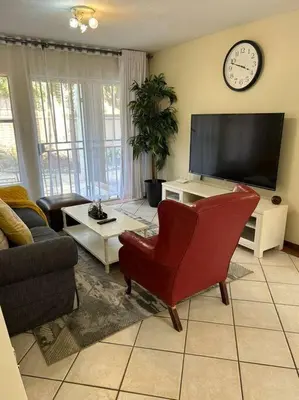 a living room with a tv and a red chair at 2c - 4 No load shedding 2bed 2bath with garden in Centurion