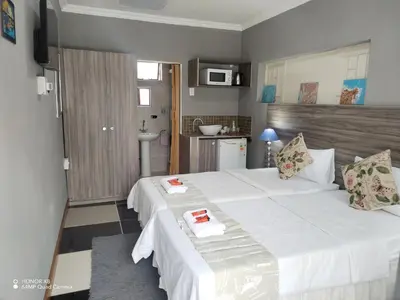 a bedroom with a large white bed and a kitchen at Home of peace and tranquility in Pretoria