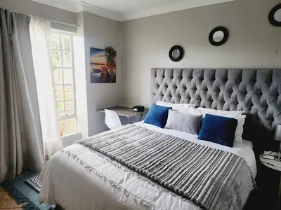 a bedroom with a large bed with blue pillows at Olympia in Pretoria