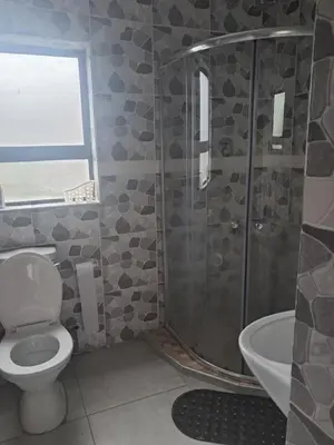 a bathroom with a shower and a toilet and a sink at Sibusisiwe 2 in Tasakani
