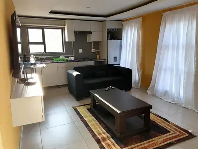a living room with a black couch and a table at Sibusisiwe 2 in Tasakani