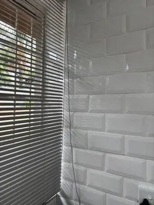 a white brick wall with blinds on a window at Soft Spaces Haven in Pretoria