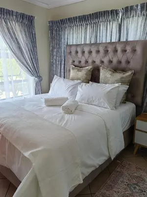 a bedroom with a large white bed with a window at The Crown in Nelspruit